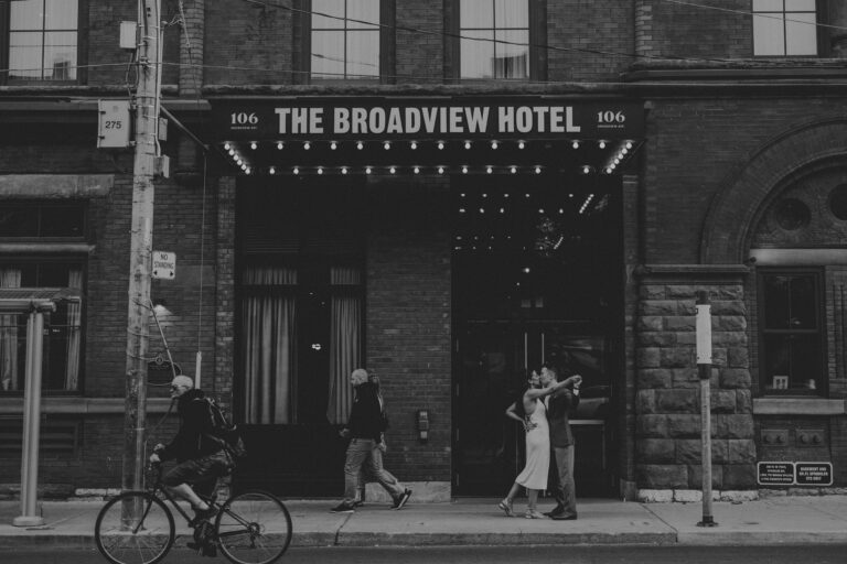 Engagement photographer in Toronto Canada takes a picture of a couple kissing right outside of the Broadview Hotel.